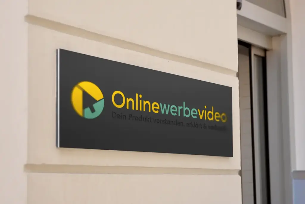 Dunkles Firmenschild von Onlinewerbevideo mit gelb-türkisem Logo, montiert an einer hellen Hausfassade. Ein Corporate Design-Projekt von foxdot.me.