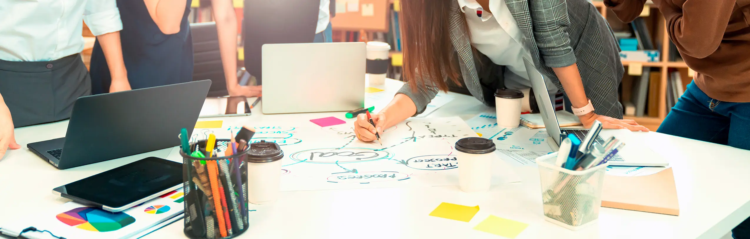 Kreatives Team erarbeitet Marketing-Strategie und Projektziele am Workshop-Tisch mit Laptops und Mindmaps.